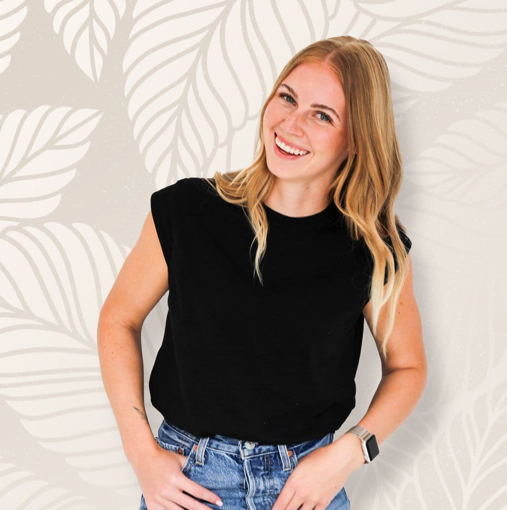 Jayslyn Tramp, licensed esthetician at Heaven Sent Beauty, standing in front of a leaf-patterned wall