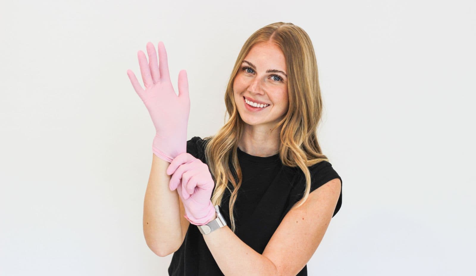 Jayslyn Tramp, licensed esthetician, pulling on pink gloves and smiling