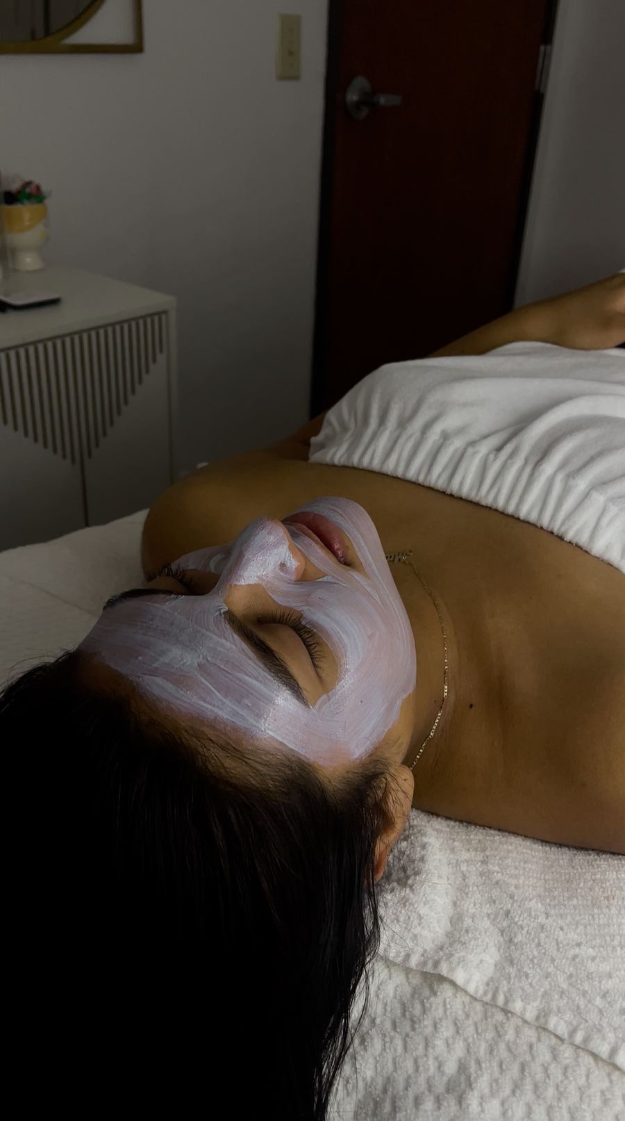 Client relaxing with a facial mask on